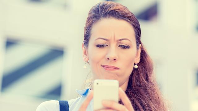 Une femme regarde son téléphone portable d'un air dubitatif. [Depositphotos - Slphotography]