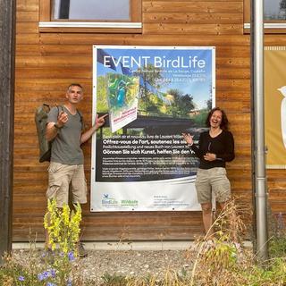 L'ornithologue et peintre Laurent Willenegger et Mélanie Tissot, directrice du Centre-Nature BirdLife de la Sauge à Cudrefin devant l'affiche de l'exposition. [RTS - Lucile Solari]