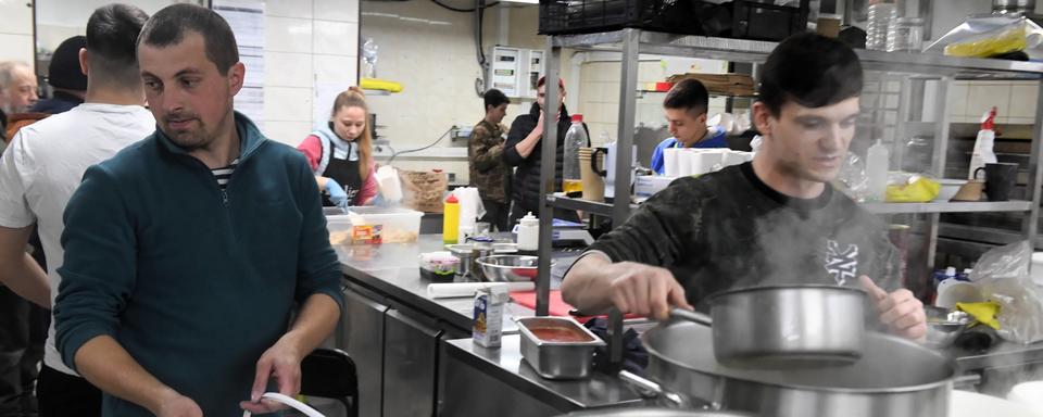 Des personnes préparent un repas pour les soldats ukrainiens engagés au front, dans la cuisine d'un restaurant de Kharkiv, le 22 mars 2022. [EPA/Keystsone - Andrzej Lange]