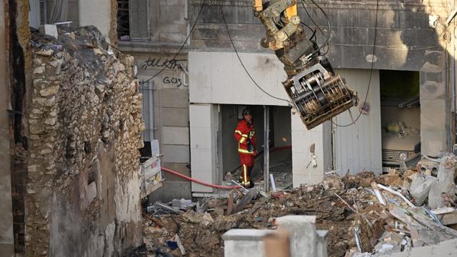 Un pompier regarde une excavatrice qui déplace des déblais sur le site d'une explosion à Marseille. [AFP - Nicolas Tucat]