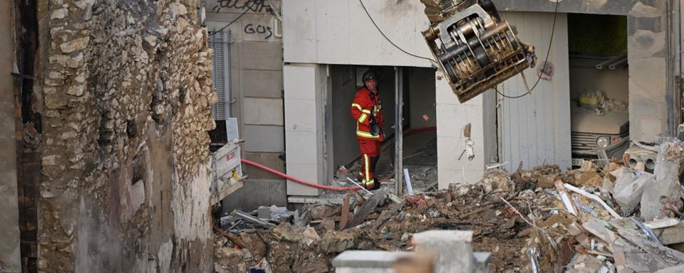 Un pompier regarde une excavatrice qui déplace des déblais sur le site d'une explosion à Marseille. [AFP - Nicolas Tucat]