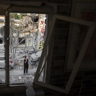 Des israéliens inspectent les débris d'un immeuble après l'attaque d'un missile du Hamas, le 8 octobre 2023. [Keystone/AP Photo - Oded Balilty]
