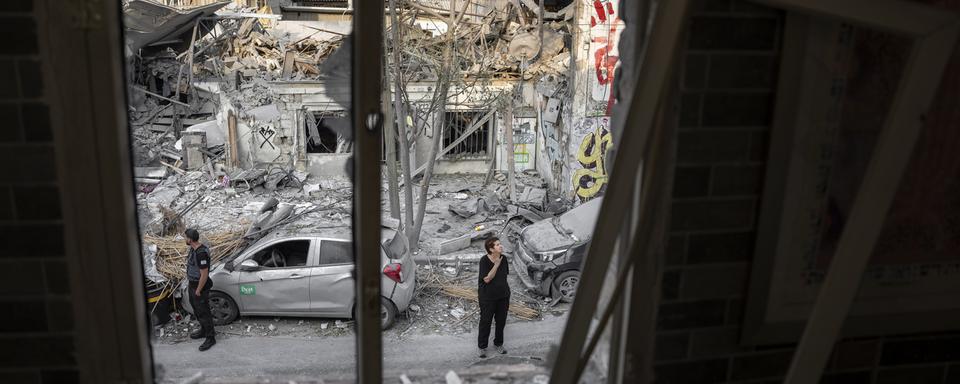 Des israéliens inspectent les débris d'un immeuble après l'attaque d'un missile du Hamas, le 8 octobre 2023. [Keystone/AP Photo - Oded Balilty]