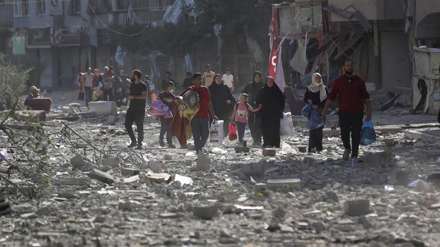 Des Palestiens au milieu d'une rue de Gaza détruite par un bombardement, le 30 octobre 2023. [Keystone/AP Photo - Abed Khaled]