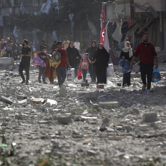 Des Palestiens au milieu d'une rue de Gaza détruite par un bombardement, le 30 octobre 2023. [Keystone/AP Photo - Abed Khaled]