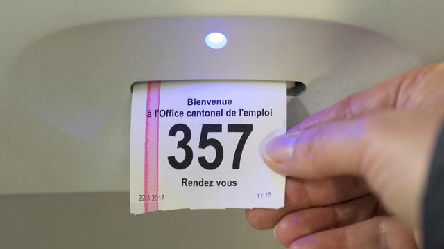 Une personne saisit un ticket de passage dans un Office régional de placement (ORP). [Keystone - Gaetan Bally]