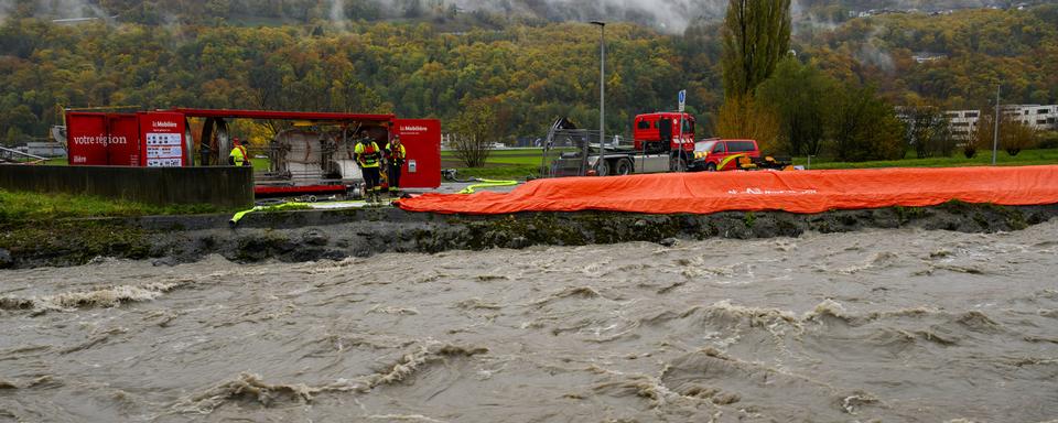 Des membres des pompiers surveillent les barrages mobiles le long de la rivière la Vièze suite aux fortes pluies le mardi 14 novembre 2023 à Monthey dans le canton du Valais (image d'archives). [Keystone - Jean-Christophe Bott]