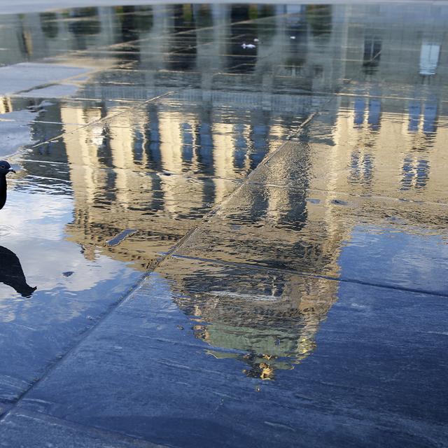 Le Palais fédéral se reflète dans l'eau sur la Place fédérale. [Keystone - Peter Klaunzer]
