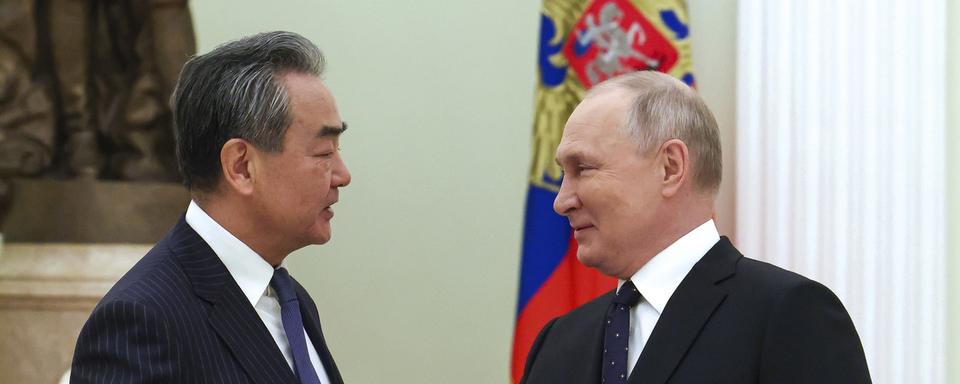 Le président russe Vladimir Poutine salue le chef de la politique étrangère du Parti communiste chinois Wang Yi lors de leur rencontre au Kremlin à Moscou le 22 février 2023. [Keystone - Anton Novoderezhkin, Sputnik, Kremlin Pool Photo via AP]