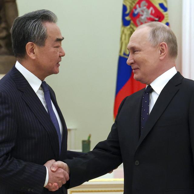 Le président russe Vladimir Poutine salue le chef de la politique étrangère du Parti communiste chinois Wang Yi lors de leur rencontre au Kremlin à Moscou le 22 février 2023. [Keystone - Anton Novoderezhkin, Sputnik, Kremlin Pool Photo via AP]