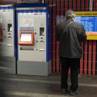 Une personne observe un horaire à côté d'un distributeur automatique de billet à la Gare CFF de Lausanne. [Keystone - Leandre Duggan]