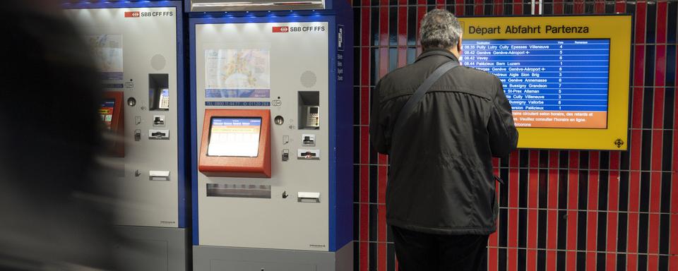 Une personne observe un horaire à côté d'un distributeur automatique de billet à la Gare CFF de Lausanne. [Keystone - Leandre Duggan]