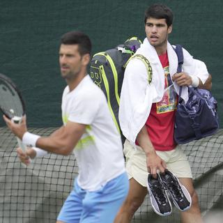 Les joueurs de tennis Novak Djokovic (gauche, Serbie) et Carlos Alcaraz (droite, Espagne) lors d'un entraînement en amont du tournoi anglais de Wimbledon, le 2 juille 2023. [keystone/AP Photo - Kin Cheung]
