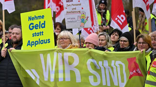 Des employés de la clinique centrale SRH de Suhl lors d'une grève d'avertissement montrent une pancarte sur laquelle on peut lire: "Prends de l'argent au lieu d'applaudir", le 13 avril 2023. [Keystone - Martin Schutt]