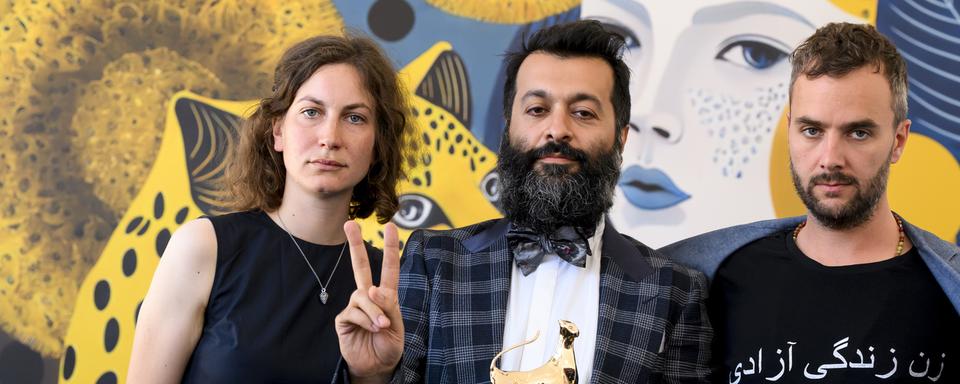 Lea Luttenberger, le producteur Sina Ataeian Dena et Alec Barth (g. à d.) avec le Léopard d'Or décerné au film iranien "Mantagheye bohrani (Critical Zone)", dont le réalisateur Ali Ahmadzadeh n'a pas pu quitter son pays. [Keystone - Jean-Christophe Bott]