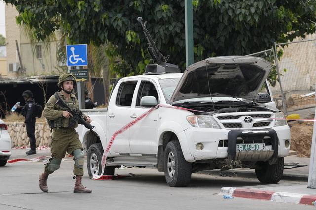 Un soldat israélien marche près d'une camionnette utilisée par des militants palestiniens à Sderot, Israël, le samedi 7 octobre 2023. [Keystone - AP Photo/Ohad Zwigenberg]