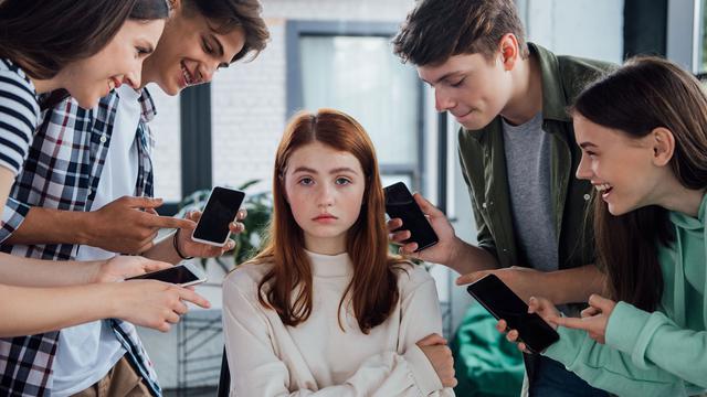 Une adolescente se fait harceler par ses camarades qui lui montrent leurs smartphones. [Depositphotos - HayDmitriy]