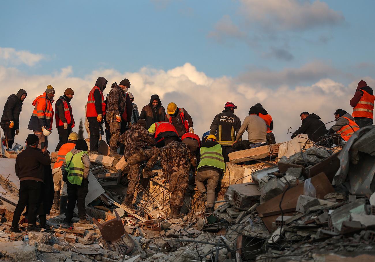 Des secouristes en train de sortir un corps d'un immeuble effondré dans la région d'Hatay, en Turquie. [Keystone - Erdem Sahin]