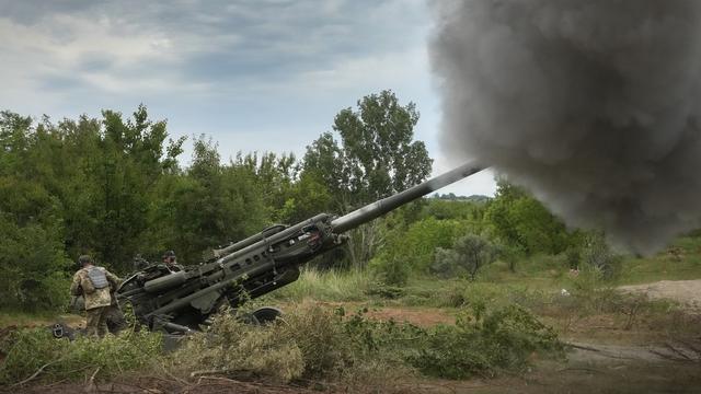 Des soldats ukrainiens se préparent à tirer sur des positions russes à partir d'un obusier M777 fourni par les États-Unis dans la région de Donetsk, dans l'est de l'Ukraine, samedi 18 juin 2022. [Keystone - AP Photo/Efrem Lukatsky]