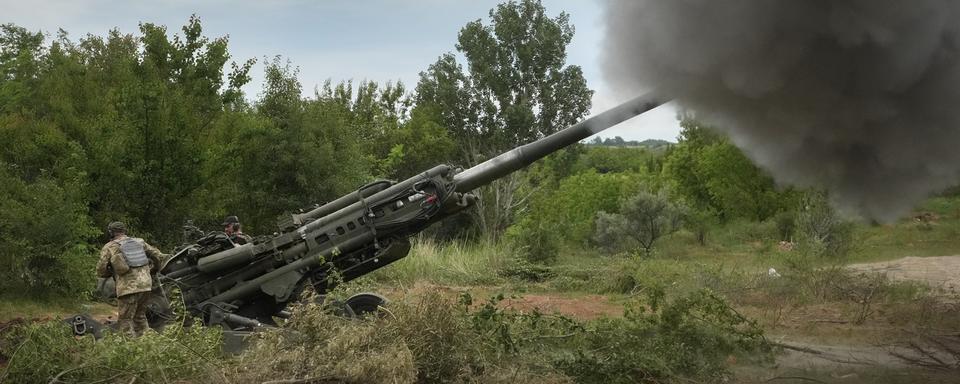 Des soldats ukrainiens se préparent à tirer sur des positions russes à partir d'un obusier M777 fourni par les États-Unis dans la région de Donetsk, dans l'est de l'Ukraine, samedi 18 juin 2022. [Keystone - AP Photo/Efrem Lukatsky]