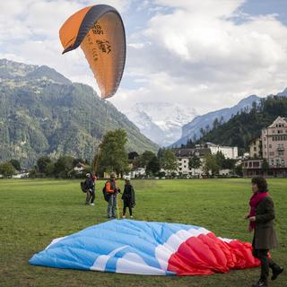 Des touristes débarquant en parapente biplace à Interlaken en 2015. [Keystone - Dominic Steinmann]
