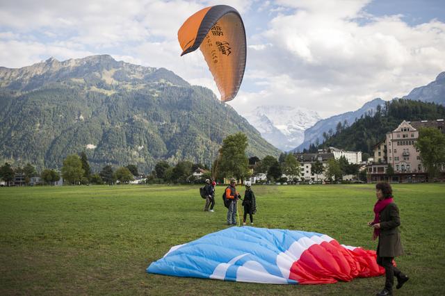 Des touristes débarquant en parapente biplace à Interlaken en 2015. [Keystone - Dominic Steinmann]