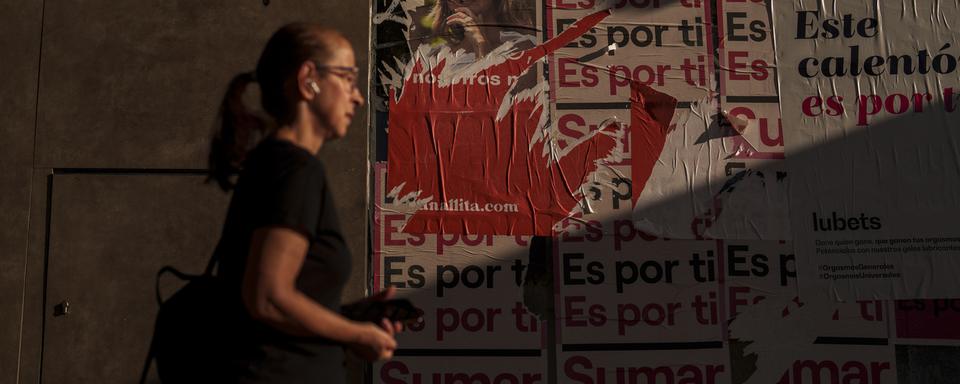 Une femme devant des affiches électorales de la gauche espagnole, juillet 2023 (image d'illustration). [Keystone/AP Photo - Manu Fernandez]