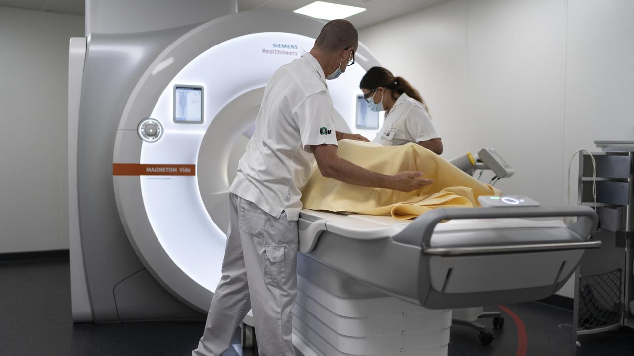Un patient est accompagné dans un IRM sous la surveillance de deux soignant.e.s. (CHUV, Lausanne, 23.08.22, image d'illustration) [Keystone - Gaetan Bally]