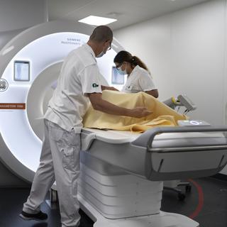 Un patient est accompagné dans un IRM sous la surveillance de deux soignant.e.s. (CHUV, Lausanne, 23.08.22, image d'illustration) [Keystone - Gaetan Bally]