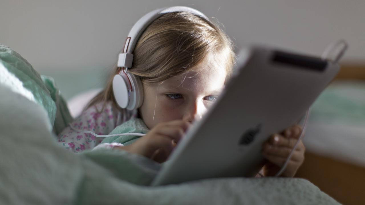Une enfant de sept ans écoute de la musique et regarde un Ipad. [Keystone - GAETAN BALLY]