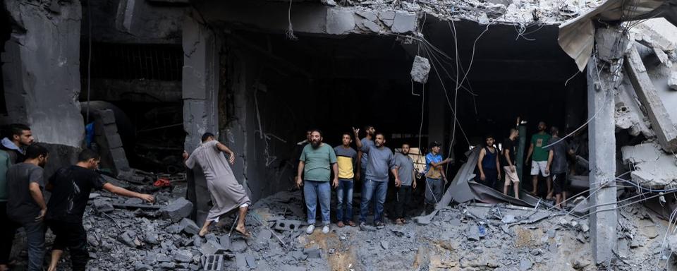 Les civils palestiniens recherchent des survivants dans les décombres d'un bâtiment touché lors du bombardement israélien à Khan Yunis, dans le sud de la bande de Gaza, le 19 octobre 2023. [AFP]