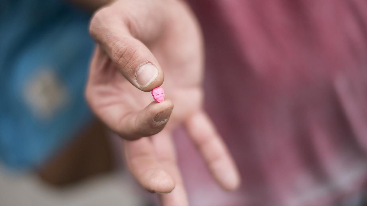 Un homme montre une pilule de MDMA, une drogue de la catégorie des amphétamines, connue pour ses effets stimulants et hallucinants (image d'illustration). [Keystone - Ennio Leanza]