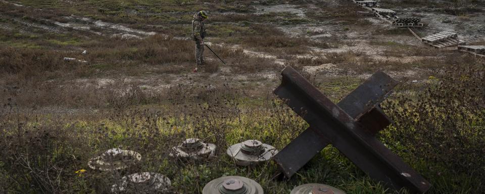 Un soldat ukrainien cherche des mines sur le terrain d'un village récemment libéré à la périphérie de Kherson, dans le sud de l'Ukraine, mercredi 16 novembre 2022 (image d'illustration). [KEYSTONE - Bernat Armangue / AP Photo]