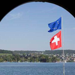 Un drapeau européen et un drapeau suisse flottent dans le vent au bord du lac de Zurich. [Keystone]