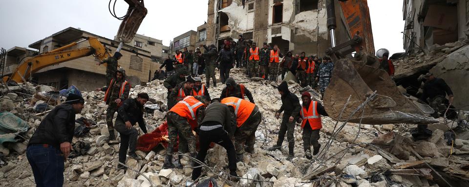 Des civils et des forces de sécurité cherchent des rescapées et des rescapés parmi les bâtiments détruits de la ville de Hama en Syrie. [Keystone/AP Photo - Omar Sanadik]