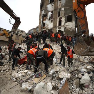 Des civils et des forces de sécurité cherchent des rescapées et des rescapés parmi les bâtiments détruits de la ville de Hama en Syrie. [Keystone/AP Photo - Omar Sanadik]