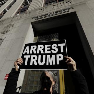 Une manifestante devant un bâtiment administratif américain, nommé d'après Louis Lefkowitz, dans lequel une potentielle arrestation de Trump par la justice new-yorkaise est en train d'être décidé. [Keystone/EPA - Peter Foley]