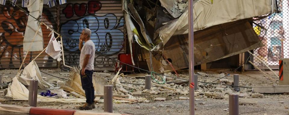 Un homme devant la devanture endommagée d'un magasin de Tel Aviv. [afp - JACK GUEZ]