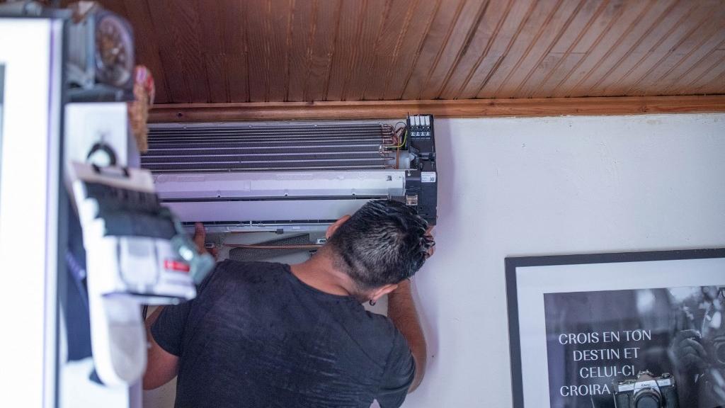 Un homme installe une climatisation dans une maison. [afp - Roland Macri / Hans Lucas]