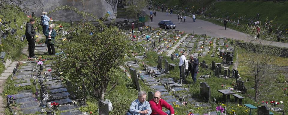 Des Ukrainiens rendant visite à leurs proches défunts dans un cimetière. [EPA / Keystone - Sergey Dolzhenko]