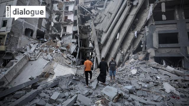 Des Palestiniens au milieu des débris d'un bâtiment détruit par une frappe israélienne à Gaza, le 8 octobre 2023. [EPA/Keystone - Haitham Imad]