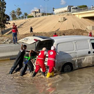 Des volontaires du Croissant-Rouge libyen dans une rue inondée, le 11 août. [Keystone - EPA]