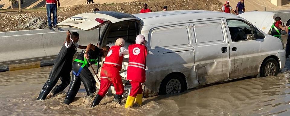 Des volontaires du Croissant-Rouge libyen dans une rue inondée, le 11 août. [Keystone - EPA]