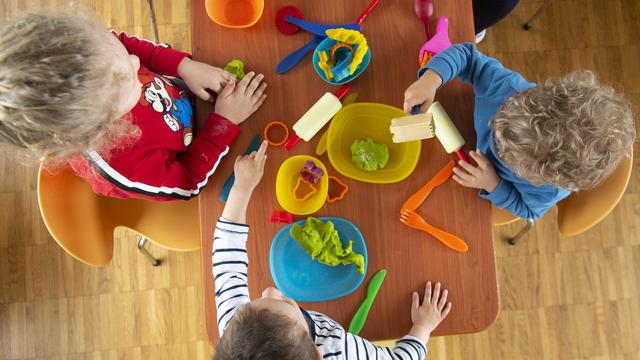 Des enfants effectuent de la pâte a modeler dans le secteur garderie de la crèche privée Nursery-Garderie Petites Couleurs en 2020. [Keystone - Laurent Gilliéron]