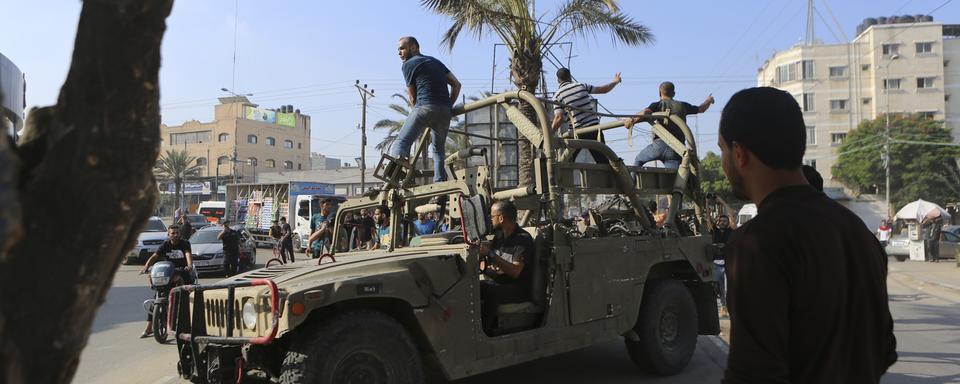 Palestinians ride on an Israeli military vehicle taken by an army base overrun by Hamas militants near the Gaza Strip fence, in Gaza City, Saturday, Oct. 7, 2023. (AP Photo/Abed Abu Reash) [Keystone/AP - Abed Abu Reash]