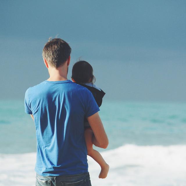 Un parent et son enfant se tiennent de dos, face à la mer. [Unsplash - Steven Van Loy]