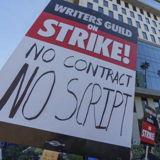 Une gréviste américaine dénonce "une rémunération abusive et une précarité contractuelle mondiale". [Keystone/AP Photo - Damian Dovarganes]