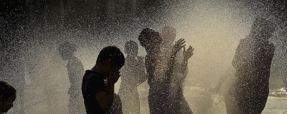 Des enfants jouant dans une fontaine à eau, au nord de l'Espagne à Pampelune. [Keystone/AP Photo - Alvaro Barrientos]