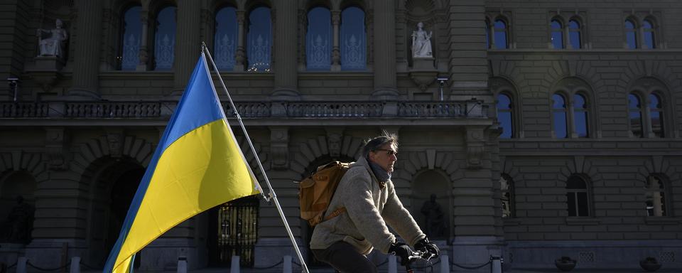 Un homme proteste contre la guerre en Ukraine devant le Parlement suisse. [Keystone - Anthony Anex]