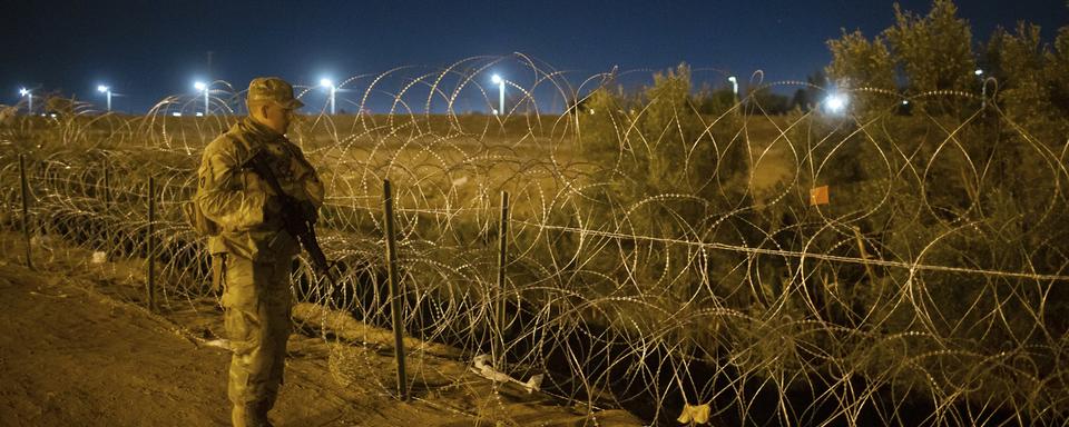 Jeudi 11 mai: un soldat de la Garde nationale du Texas inspecte les barbelés le long du Rio Grande près d'un rassemblement de migrants qui attendent à une porte de la clôture frontalière à El Paso, au Texas. Les migrants se sont précipités à la frontière quelques heures avant l'expiration des restrictions à l'asile liées à la pandémie, craignant que les nouvelles politiques ne rendent l'entrée aux États-Unis beaucoup plus difficile. [Keystone - AP Photo/Andres Leighton]